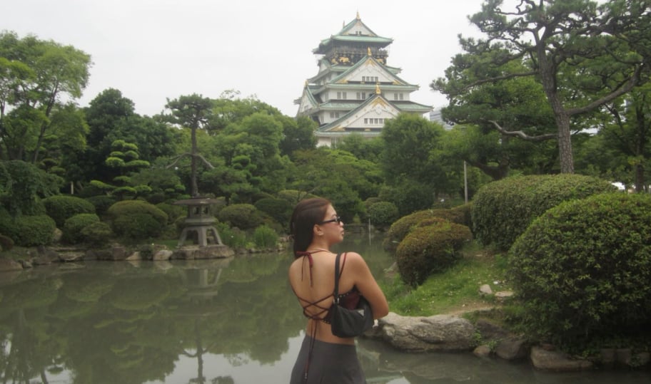 城の天守を望む日本庭園の池のほとりに立つ旅行者